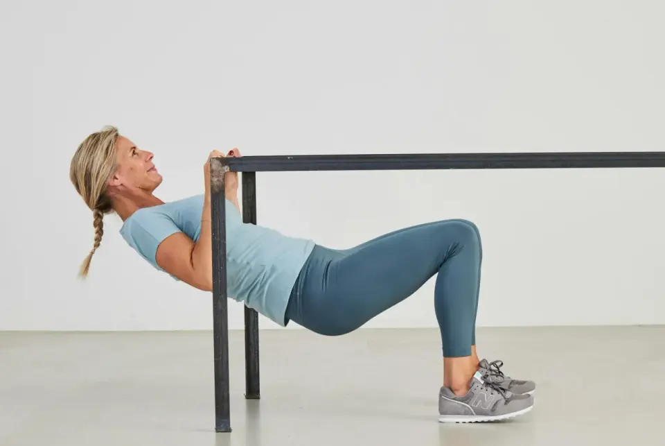 Kvinna utför overhead triceps extension vid en ställning.